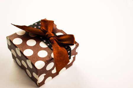 Christmas present with a bow lies on a white table. A small gift on a white background. Merry...