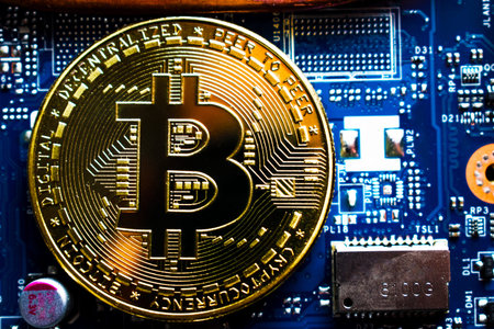 Golden bitcoin on laptop motherboard.