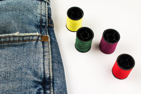 Four reels of thread and jeans. Sewing as hobby.