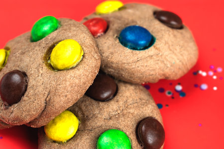 Fresh Christmas cookies with colorful candies on a red background. Homemade Christmas cookies
