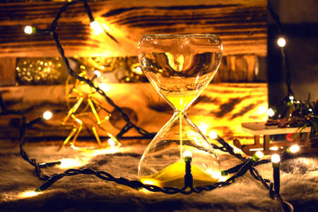 Hourglass on the background of a box with toys for the Christmas tree. For the moment, before Christmas.の写真素材