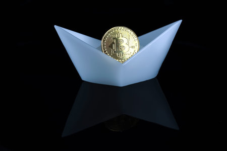 A bitcoin coin in a white boat on a black background. Crypto Industry.