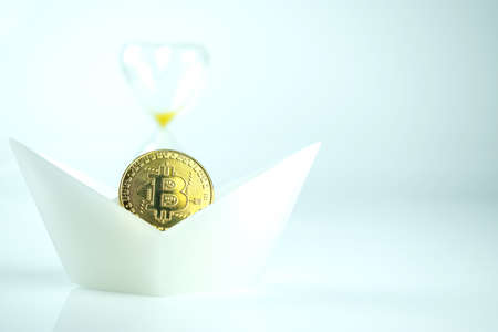 A bitcoin coin in a white ship with an hourglass. The collapse of cryptocurrencies.の写真素材