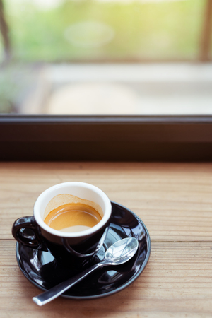 Espresso coffee is placed on a wooden desk at the window.の写真素材