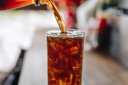 Pouring cola water into the glass.Cola in summer. Cola soda. Cola at the party.の写真素材