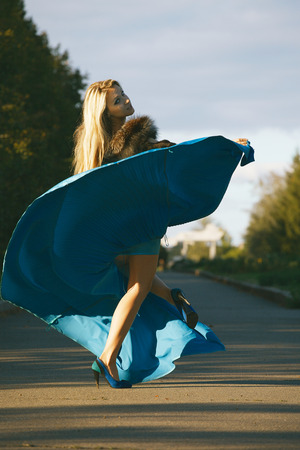 elegant woman in blue dress whirls and enjoying life in the park の写真素材