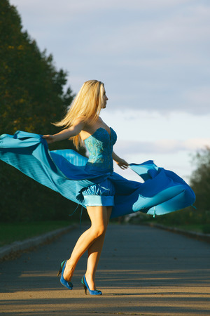 elegant woman in blue dress whirls and enjoying life in the park の写真素材