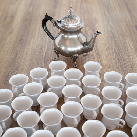 Vintage Coffee Pot On Wooden Surface With Many White Cupsの写真素材