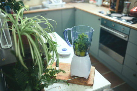 Blender in kitchen with greens