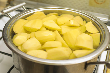 sliced raw potatoes in a saucepan, filled with water, standing on a gas stove. Hot freshly cooked vegetablesの写真素材