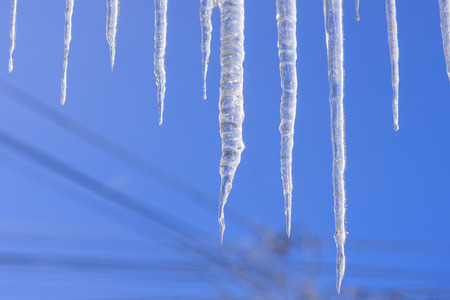 The frozen water turned into icicles hanging from the roofの写真素材