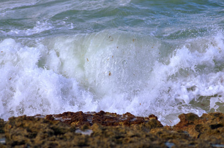 a sea wave rolls over a stony shore