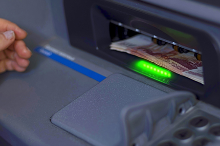 A bundle of paper money is inserted into the open ATM receiverの写真素材