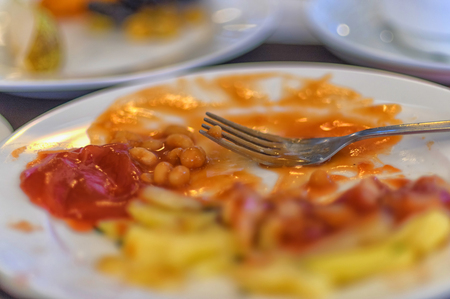 Dirty fork and plate with leftovers after breakfastの写真素材