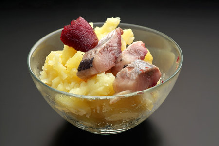 Boiled potatoes with herring and herring caviar in a transparent bowl, close-upの写真素材