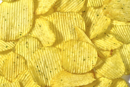 Corrugated potato chips with green onions, close-up food background, texture