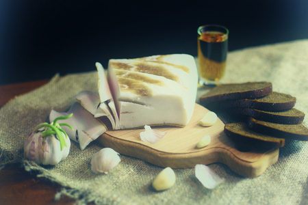 Bread lard garlic and a glass of alcohol on sackcloth vintage, tinting, defocusの写真素材