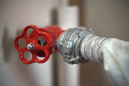 Connection of a fire hose with a red fire cock, close-upの写真素材