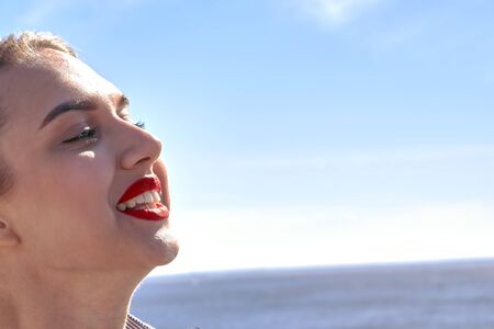 Face of a happy girl, smile on a background of sea and sky on a summer sunny dayの写真素材