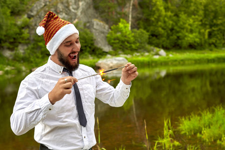 Businessman or office worker, holding a burning Bengal candle in his hand. On the head Christmas hat...