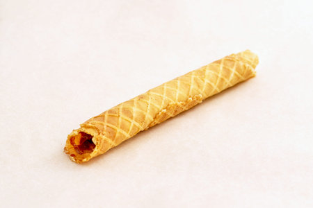 Fresh ispijena Golden waffle tube with a filling. Pastry closeup on a light background, a diagonal...