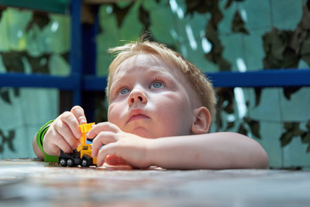 Portrait of a child of three years old playing a typewriter at the table. The kid dreamily looks up...