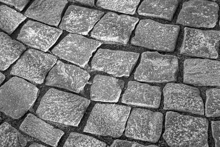 Fragment of an old road from square blocks. Granite pavement close up. Black and white shotの写真素材