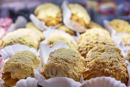 Fragment of a bakery showcase, close up. Eclair cakes on paper stands