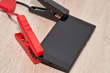 crocodile clips are connected to the body of the smartphoneの写真素材