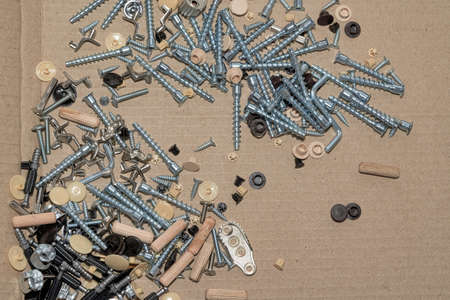 Screws and furniture fittings against the background of cardboard from packagingの写真素材