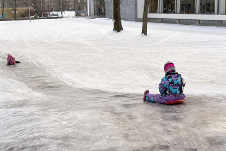 A child rides on an ice slide on a plastic sleighの写真素材