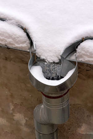 Rain drain into a pipe covered with snowの写真素材