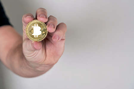 Hand holds coin with bitcoin symbol imageの写真素材