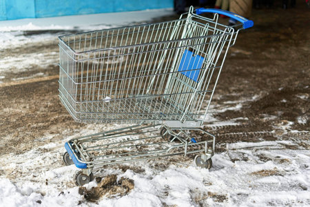 Metal shopping trolley from a supermarket. stands in snow and mud on outdoor
