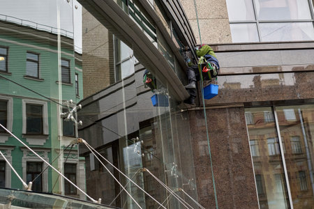 window cleaner in climbing gear washes windows on upper floors in St. Petersburg