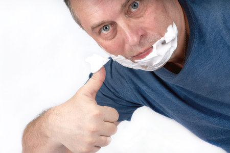 A man applies shaving foam to his face with a shaving brush