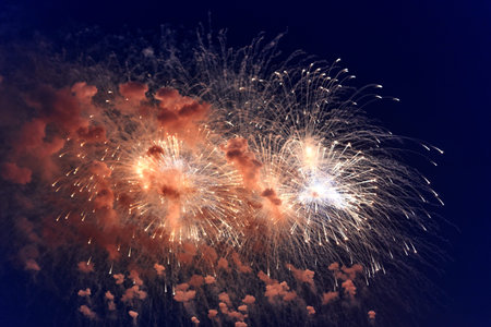 Blurred multicolored fireworks lights against the dark night sky. Festive fireworks. Light defocus