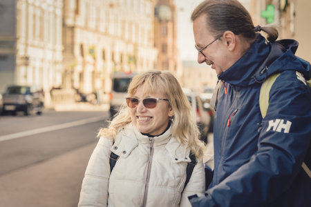 A tall man with a ponytail is talking to a woman in the street. Spring sunny day
