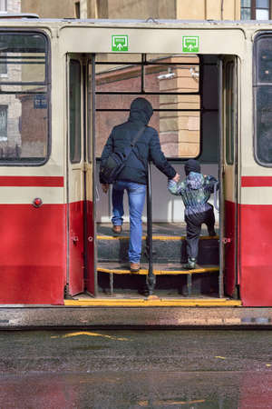 A man and a child walk through the open doors of public transport in the cityの写真素材