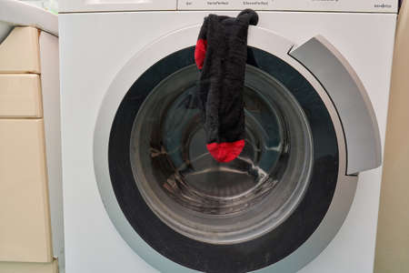 A clean black sock hangs on the door of the washing machineの写真素材