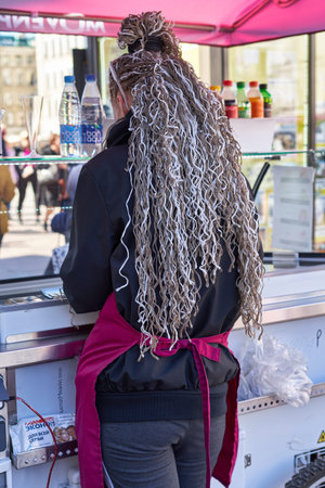 A kiosk saleswoman with long curly hair sells on the street of St. Petersburg