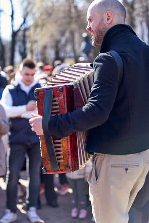 Street musician plays accordion in front of city residents in Saint Petersburgのeditorial素材