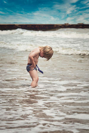 A little boy went into the sea and bent over taking off his panties. Family vacation by the seaの写真素材