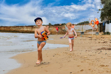 Two little boys are playing on the seashore. Children playing on the beachの写真素材