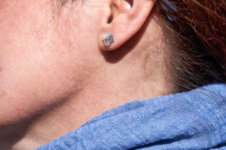 Fragment of a woman face, an ear with a glass earringの写真素材