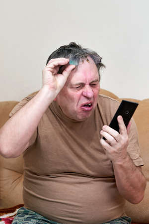 Senior citizen sitting on the couch understands the gadget, mastering smartphoneの写真素材
