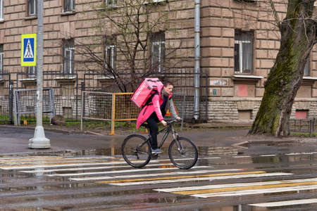 A food delivery man on a bicycle rides a crosswalkのeditorial素材