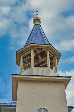 Fragment of the bell tower of a Christian church with a blue roof. Church bell tower against the skyの写真素材