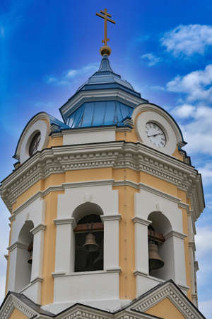 Fragment of the bell tower of a Christian church with a blue roof. Church bell tower against the skyの写真素材