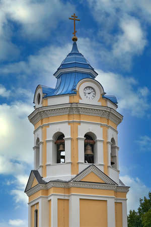 Fragment of the bell tower of a Christian church with a blue roof. Church bell tower against the skyの写真素材